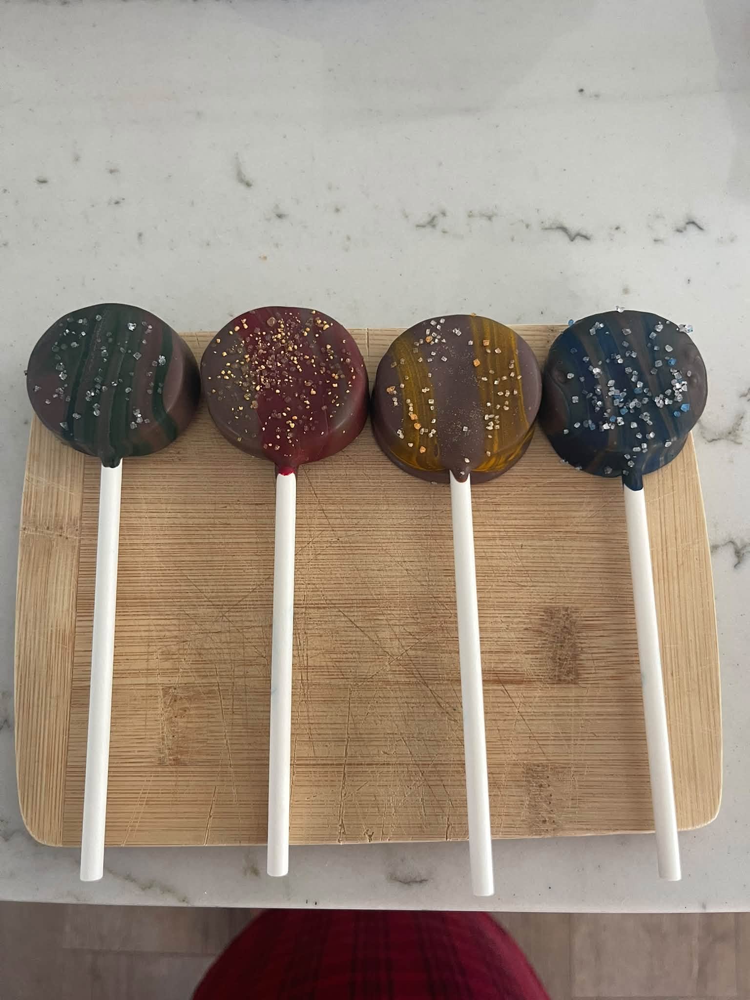 Round decorated chocolate lollipops on a wooden board