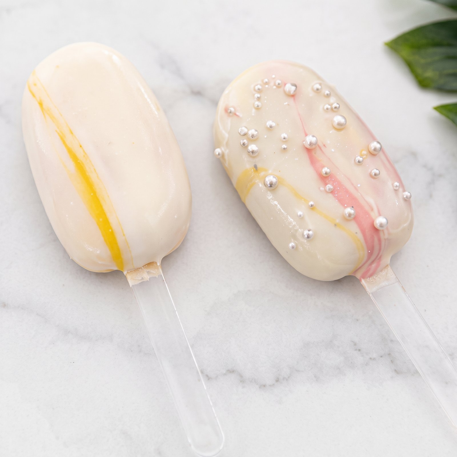 Two cakesicles with yellow and pink swirls